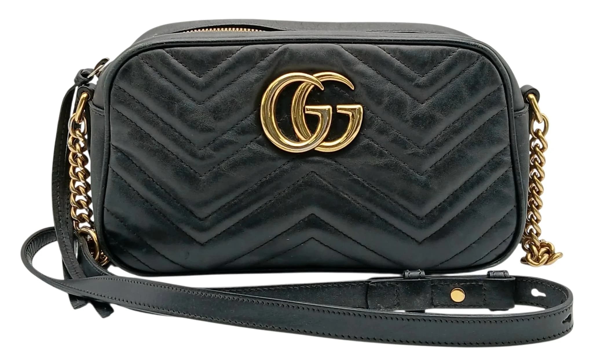 A Black Gucci GG Marmont Small Camera Shoulder Bag. Black chevron quilted leather exterior with gold-tone hardware, signature Double G logo to the front and an embossed Double G motif to the back. Zip-around closure with an adjustable leather and chain shoulder strap. Light brown suede interior with one main compartment and an open inner side pocket. Comes with dust cover bag and box. Approx. 24cm length x 13.7cm height x 7cm depth. Signs of wear to the leather exterior and corners, with marks and stains to the interior. Please see photos or request a condition report. Ref: 29669.