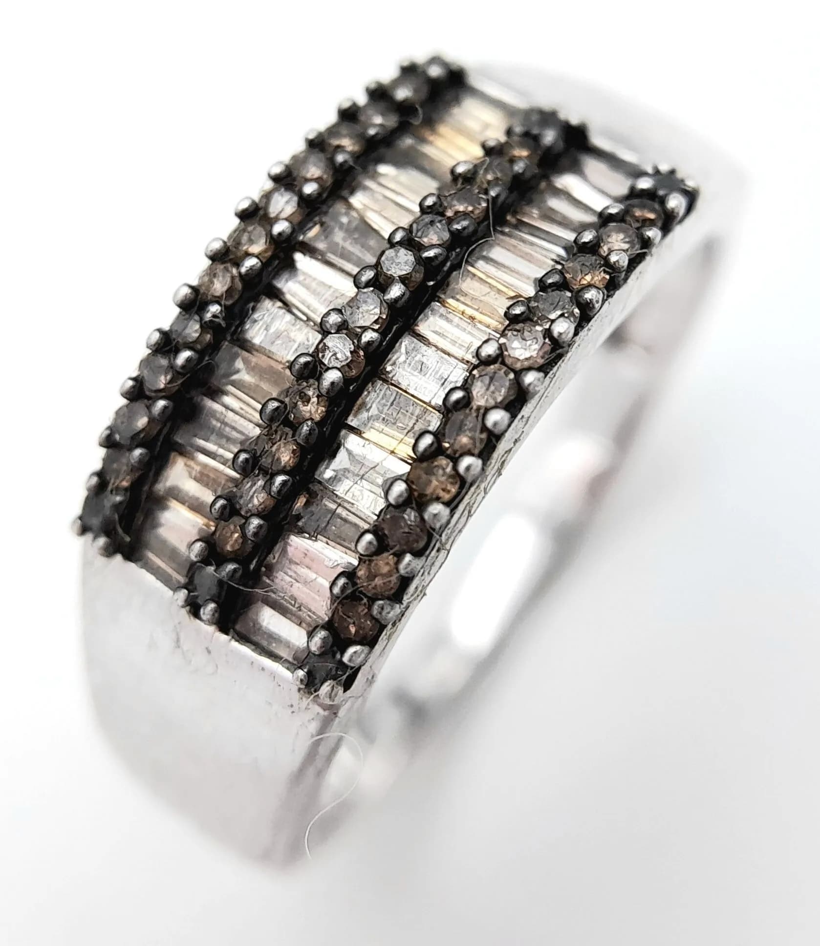 A Sterling Silver Champagne Diamond Set Ring Size S. The Ring measures 8mm wide at the Crown and is set with Baguette and Round Cut Diamonds, approximately 0.45 carat total. The Ring weighs 3.18 grams