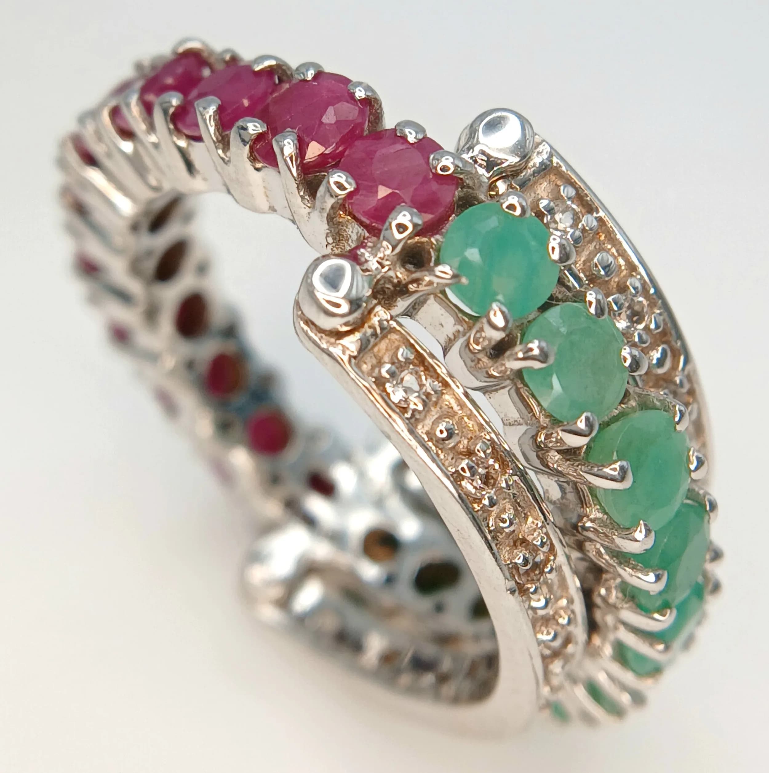 An Impressive Sterling Silver Emerald and Ruby Set Eternity Ring-Size R. The Ring is set with Ten 3mm Round Cut Emeralds and Eleven 3mm Round Cut Rubies, approximately 2.25 carat total. The Ring weighs 7.35 grams.