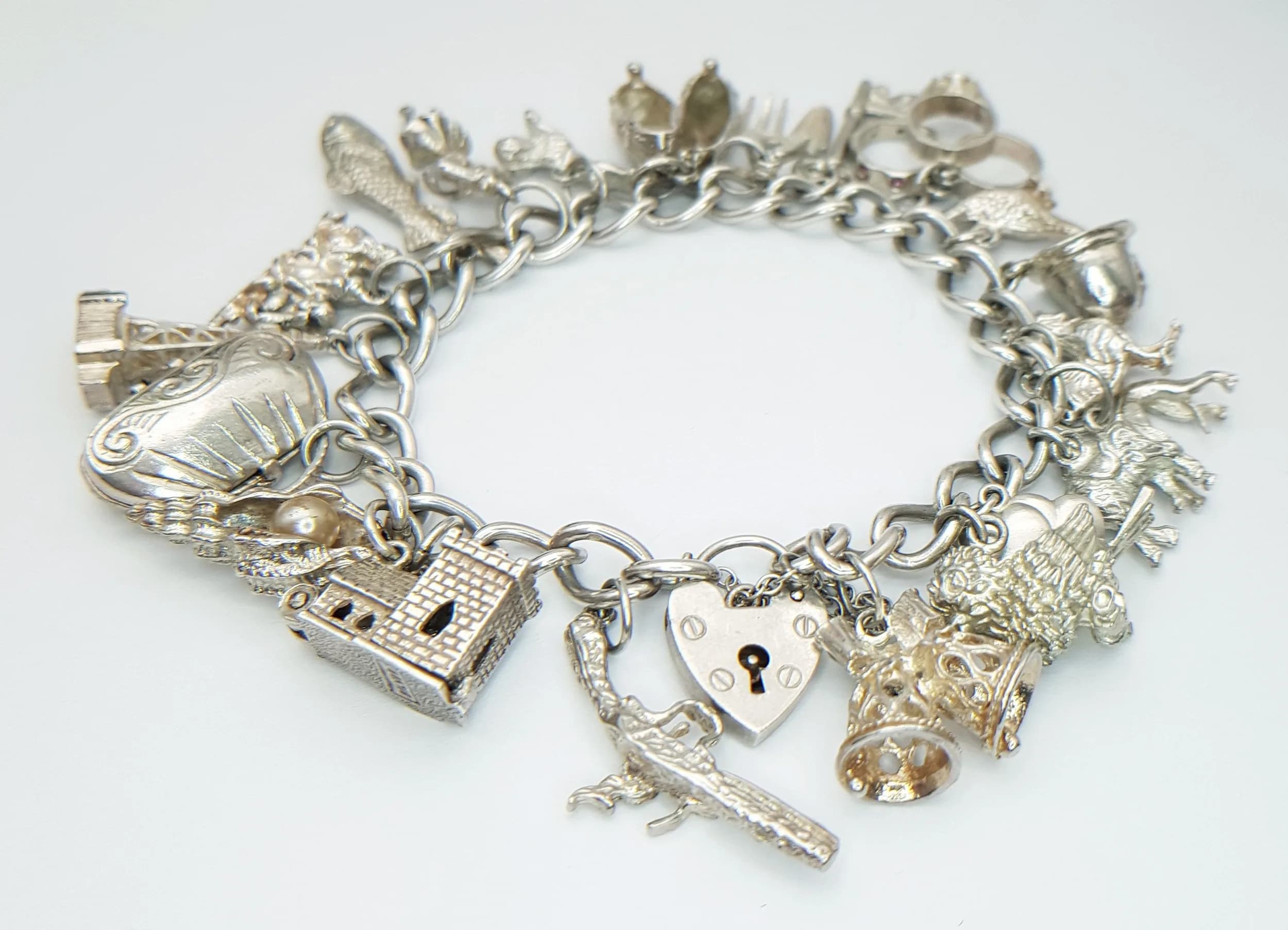 Vintage SILVER CHARM BRACELET. Having Padlock Fastening with Silver Safety Chain. Full of interesting and Unusual SILVER CHARMS (21 Total ). Approx 67 Grams.
