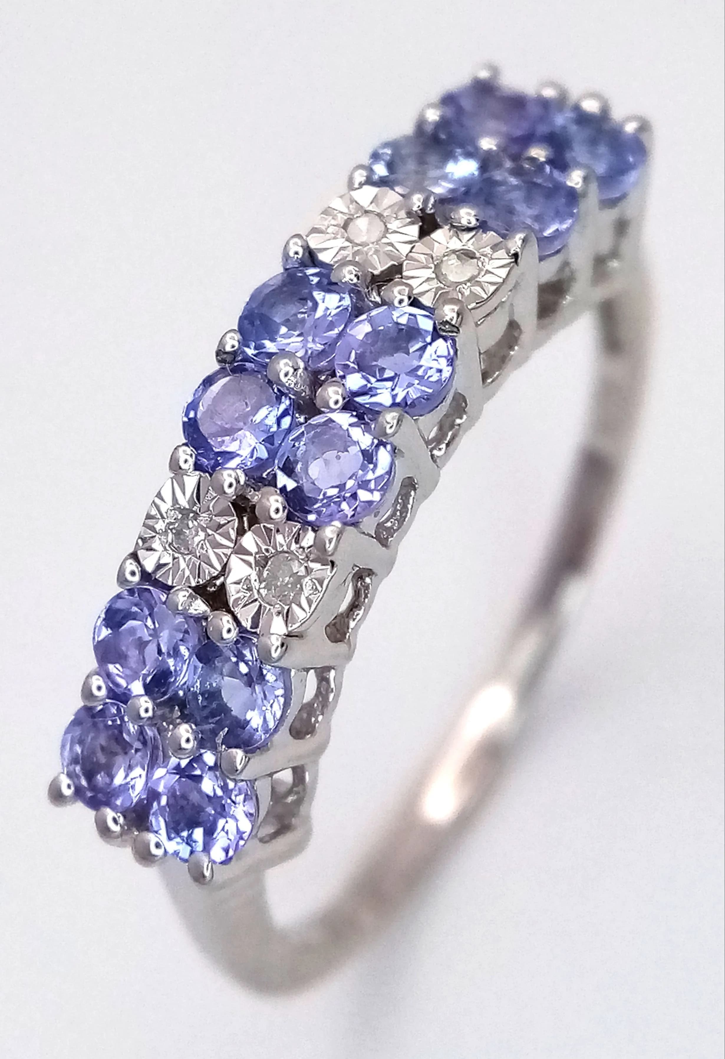 A Sterling Silver Tanzanite and Diamond Ring Size S. The Ring is set with Twelve 3mm Round Cut Tanzanite, circa 1.2 carat total and Four 1 to 1.5mm Illusion Set Diamonds. The Ring weighs 2.61 grams.