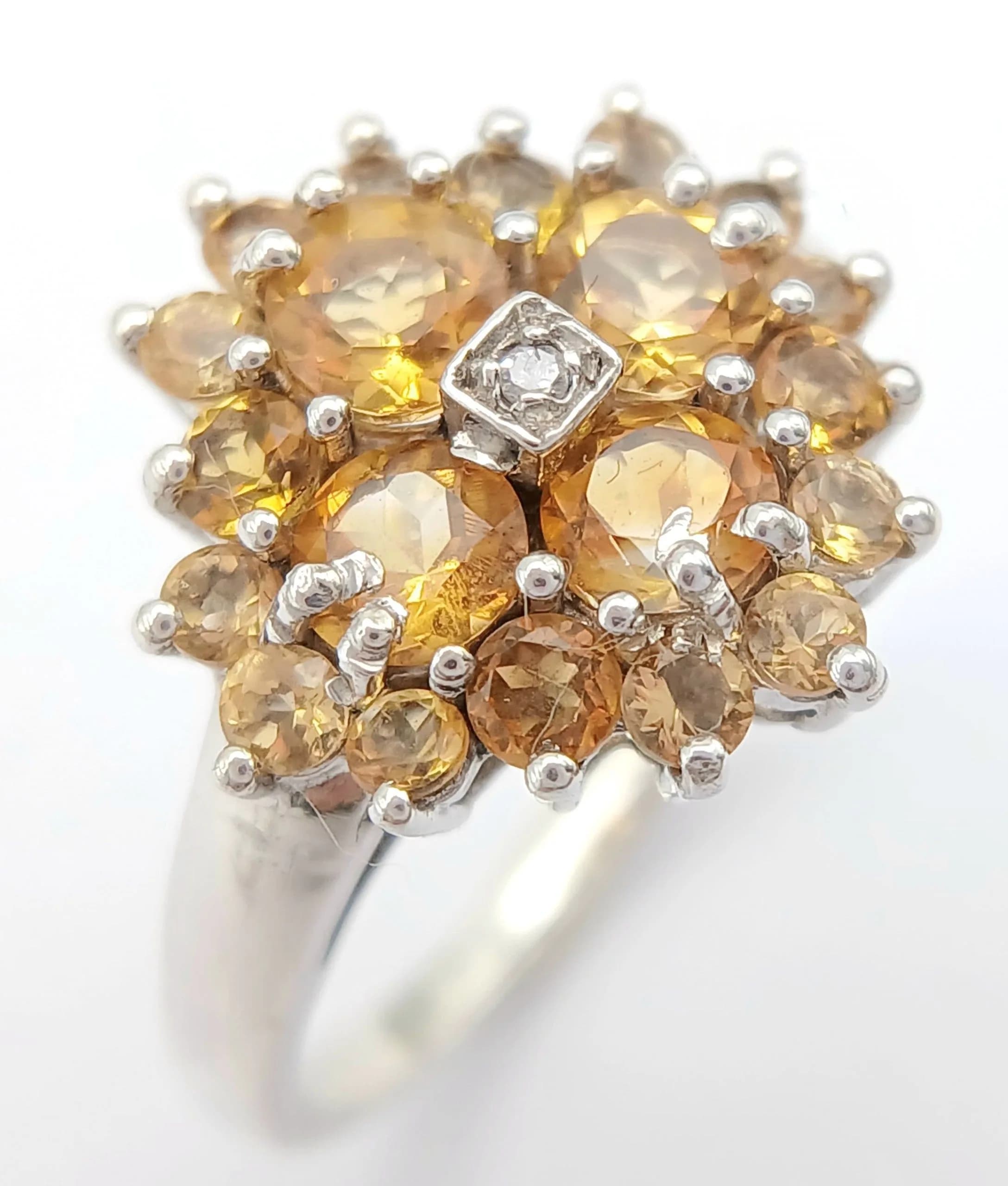 A Beautiful Sterling Silver Citrine and Diamond Ring Size O. The Crown measures 1.5cm Wide and is set with a centre round cut Diamond, surrounded by Citrine. Gross weight 3.15 grams.