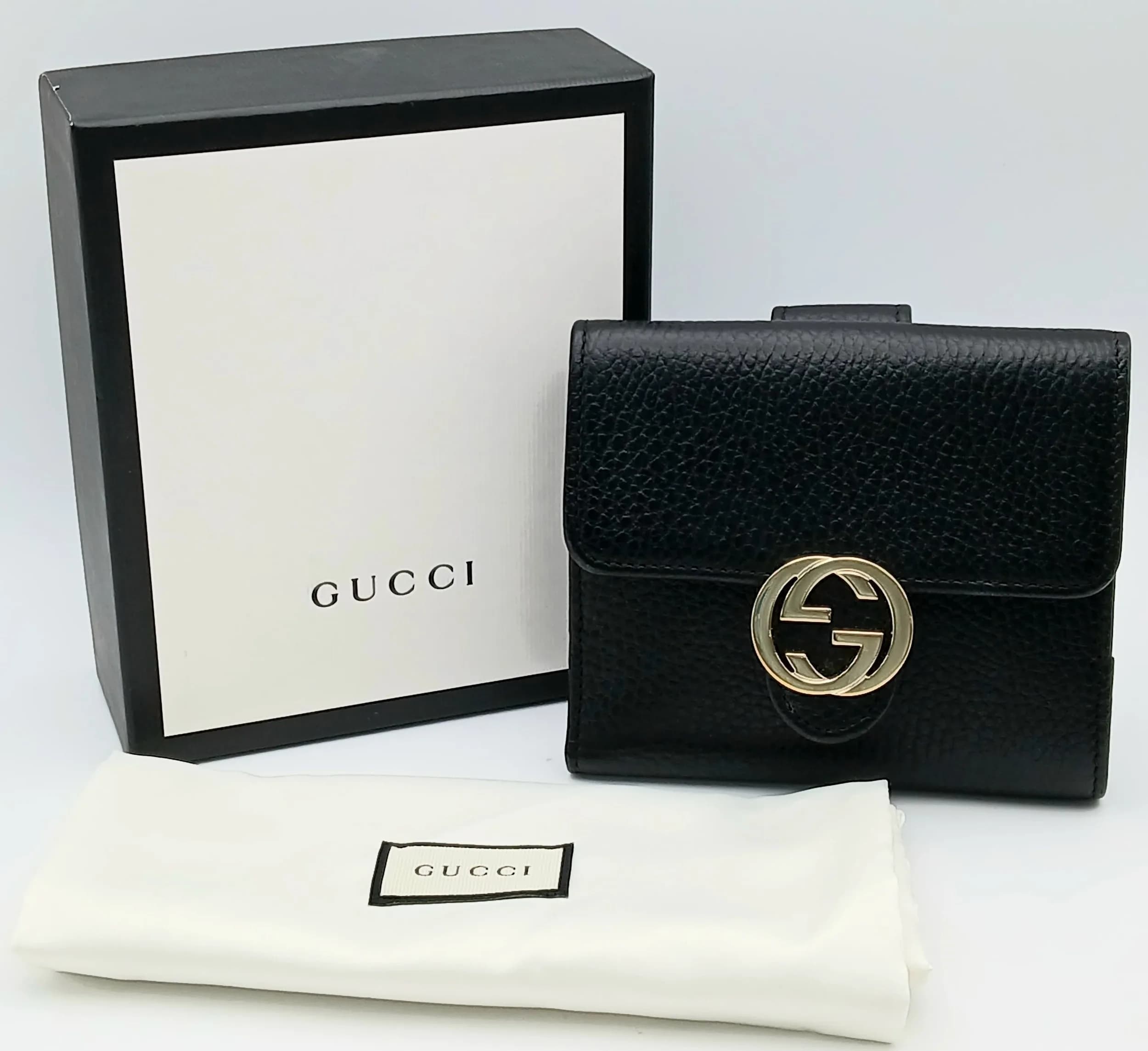 A Gucci Dollar Calfskin Interlocking G French Wallet. Black grained leather exterior with a gold-tone Interlocking G emblem to the front. Press-stud flap closure opens to a black leather interior with multiple card slots, note compartments and additional slip compartments. Rear coin pocket with press-stud closure. Approx. 12.2cm length x 11cm height when closed and 21.5cm x 12.5cm when opened. Comes with Gucci box, dust cover bag and booklets. Light wear to the corners, but overall in good condition. Please see photos or request a condition report. Ref: 29757.
