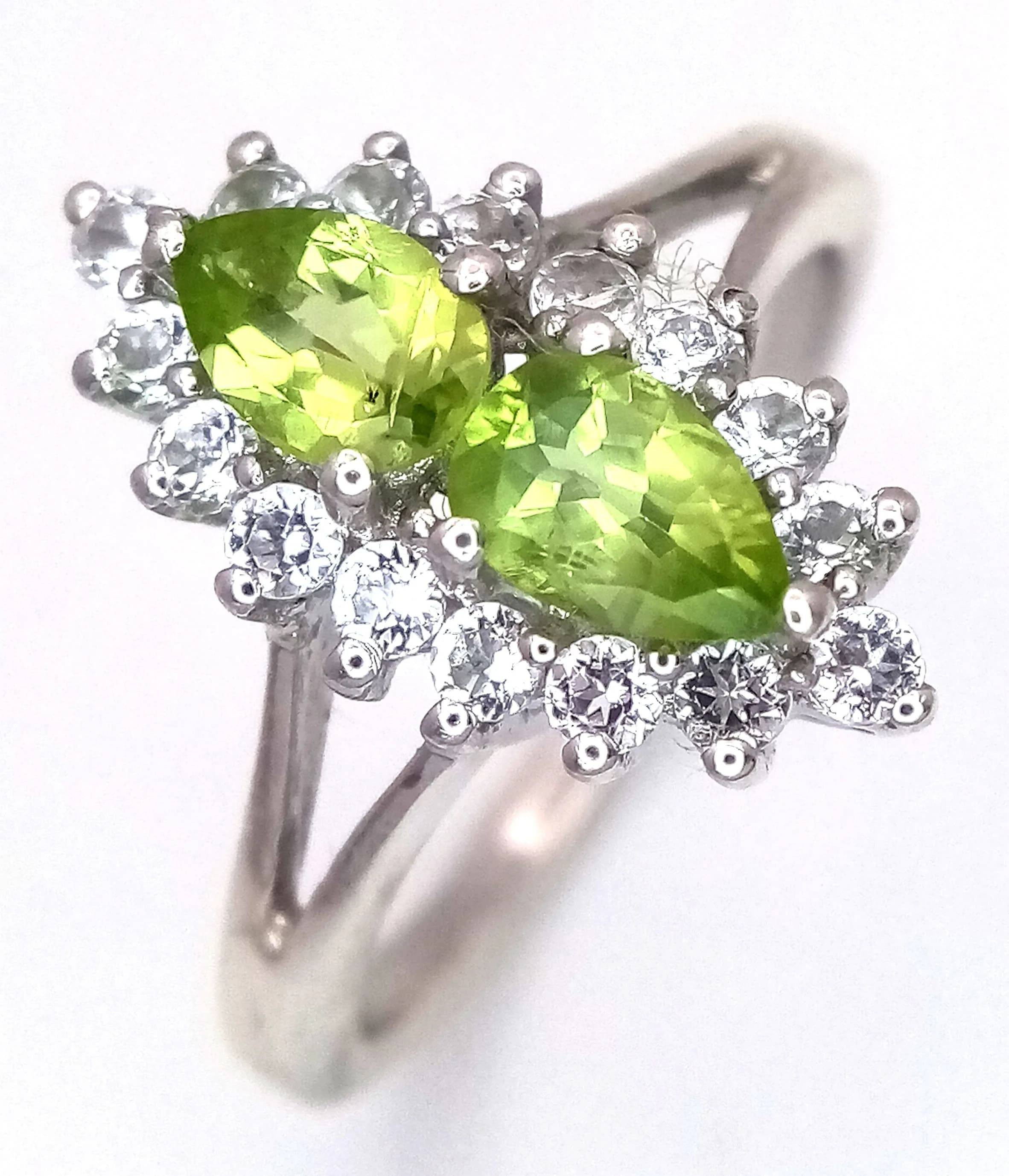 A Pretty Sterling Silver Peridot and White Topaz ‘Toi et Moi’ Ring- Size Q. The ring is set with two opposing Pear Cut Peridot, approximately 0.45 carat each and surrounded by round cut White Topaz. The Ring has a gross weight of 3.36 grams.