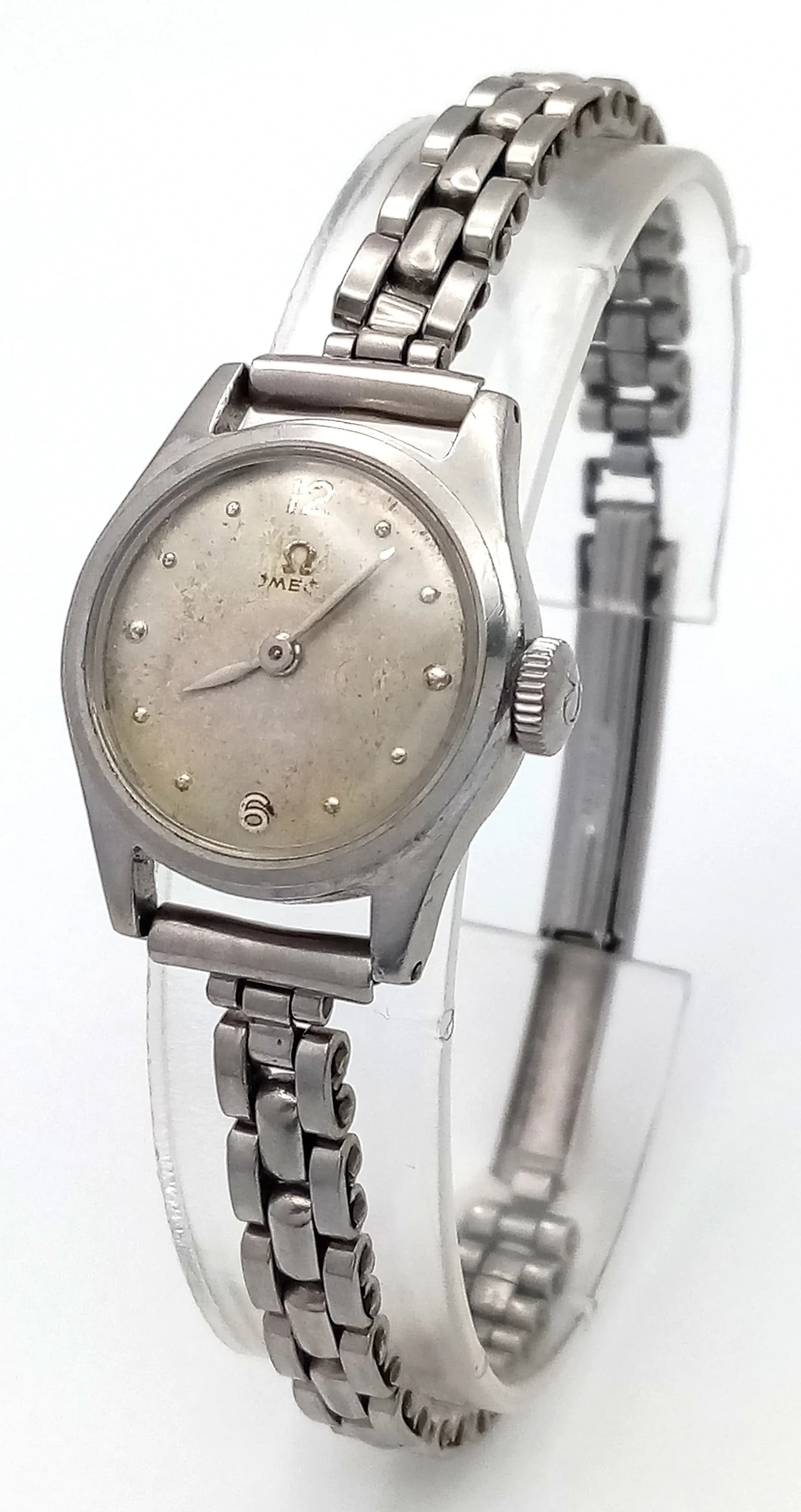A Vintage (1950s) Omega Mechanical Ladies Watch. Stainless steel bracelet and case - 22mm. Patinaed dial with Omega mark. Omega marked crown. Hand-wind. Works but because of age no guarantees.