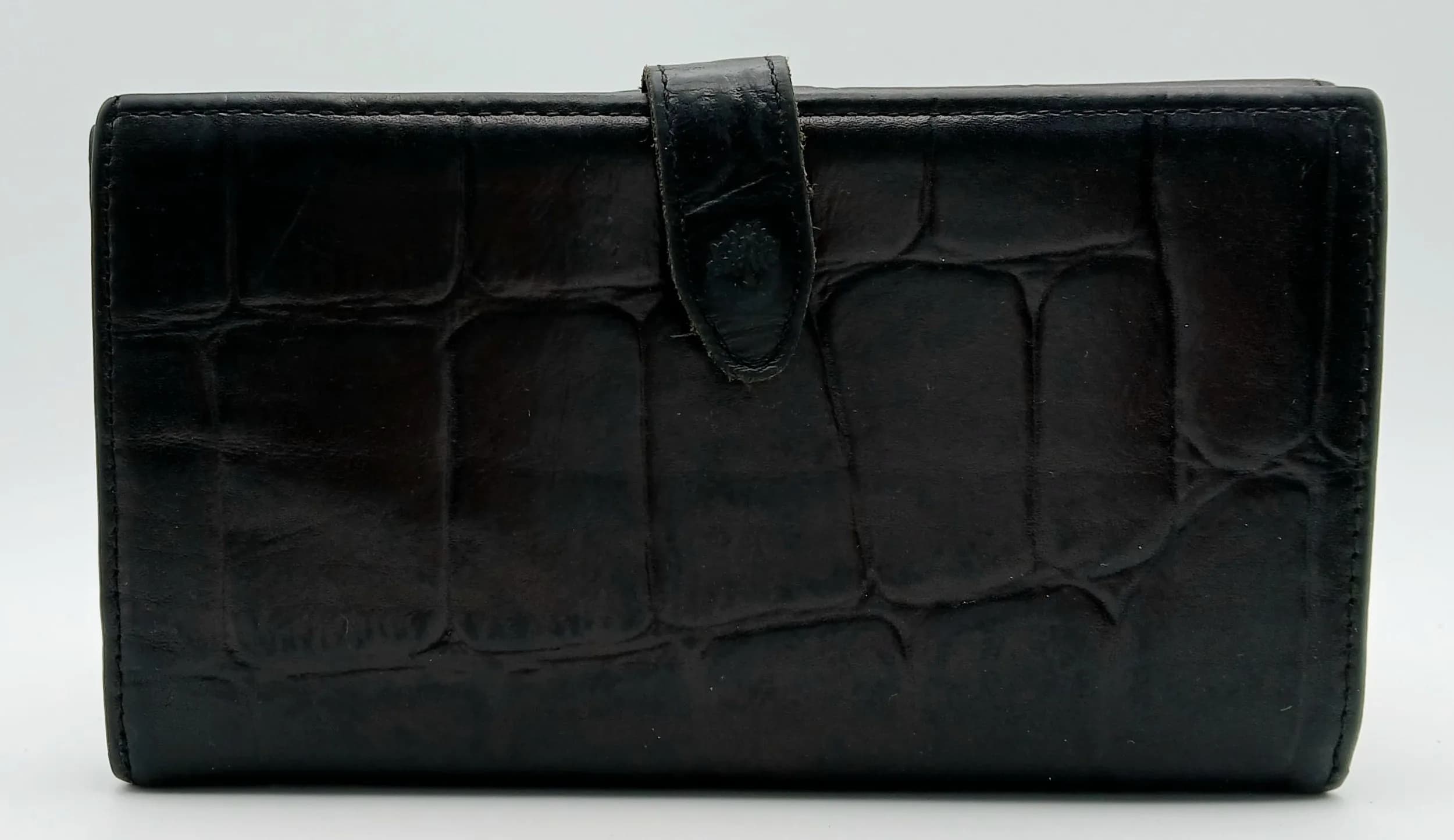 A Mulberry Black Leather Long Wallet. Black croc-embossed leather exterior with a wraparound tab and press-stud fastening. Black leather interior with multiple card slots, an ID window and divided compartments for notes and other essentials. Rear compartment with press-stud closure opens to four note compartments. Approx. 17.2cm length x 9.8cm height when closed and 19.5cm x 17.2cm when opened. Some light stains to the interior - Please see photos or request a condition report. Ref: 28470.