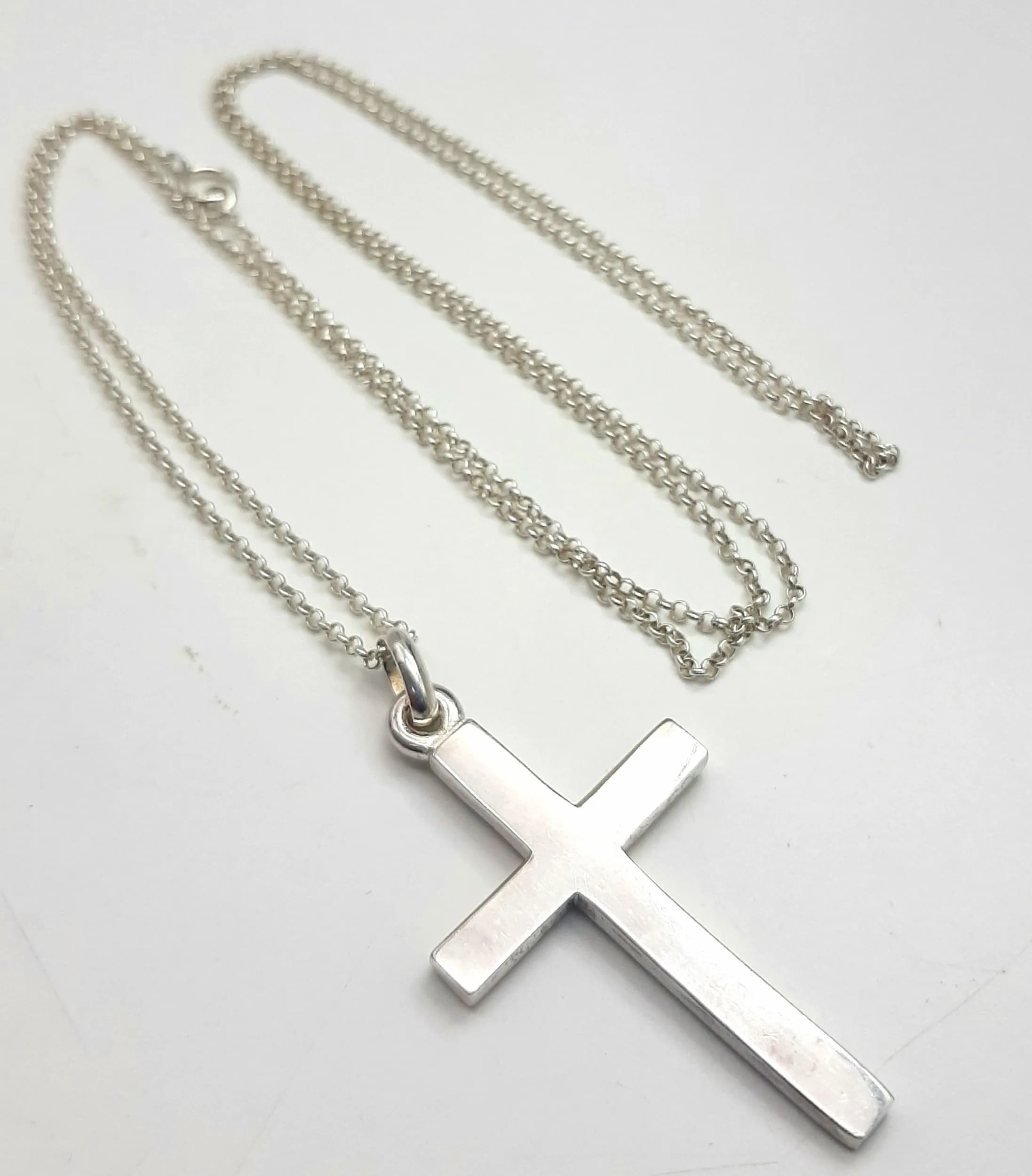A 925 Silver Cross Pendant Necklace. Plain polished cross pendant on a fine belcher chain. Both chain and cross hallmarked 925. Chain measures approx 72cm length. Cross measures 5cm drop. Total weight 10.66 grams.