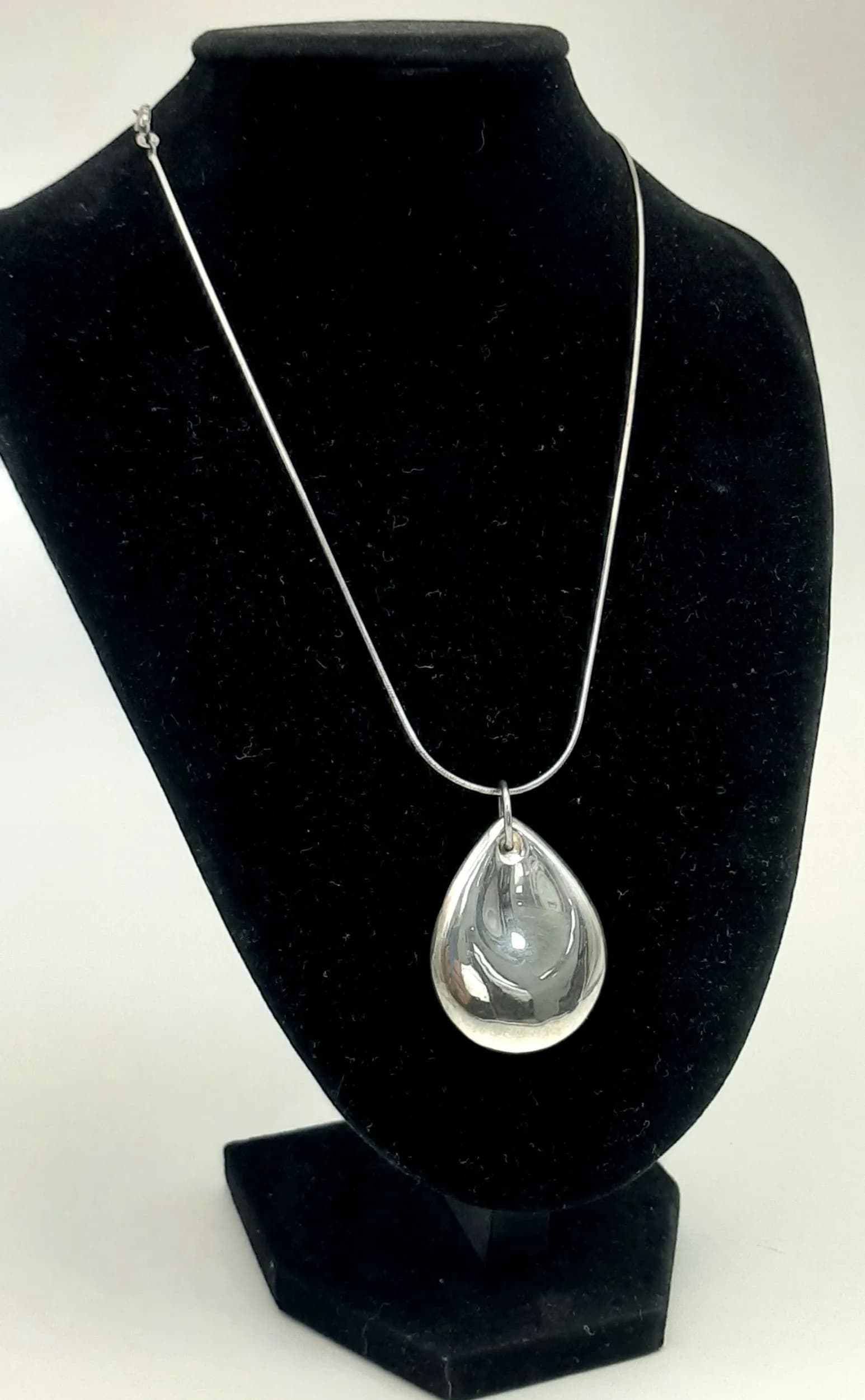 A 925 Silver Oval Pendant Necklace. The pendant has a large three-dimensional oval shape with curved edges, on a snake chain. Both pendant and chain hallmarked 925. Chain measures approx 46cm length. Pendant measures 4.5cm drop. Total weight 17.33 grams.