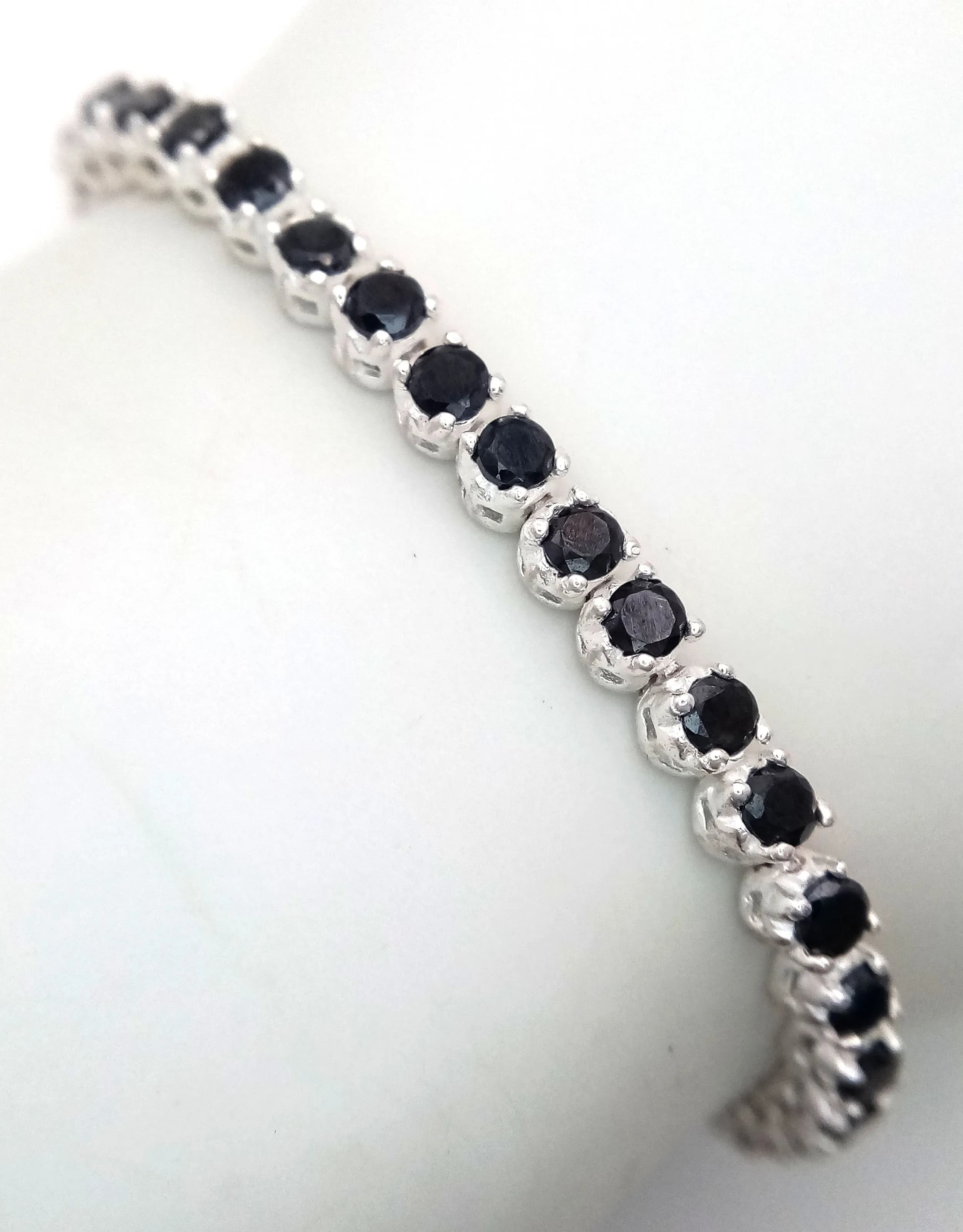 A Sterling Silver Black Cubic Zirconia Tennis Bracelet- 19cm Length. Set with 3mm round cut Black Cubic Zirconia the bracelet has a gross weight of 12.22 grams.