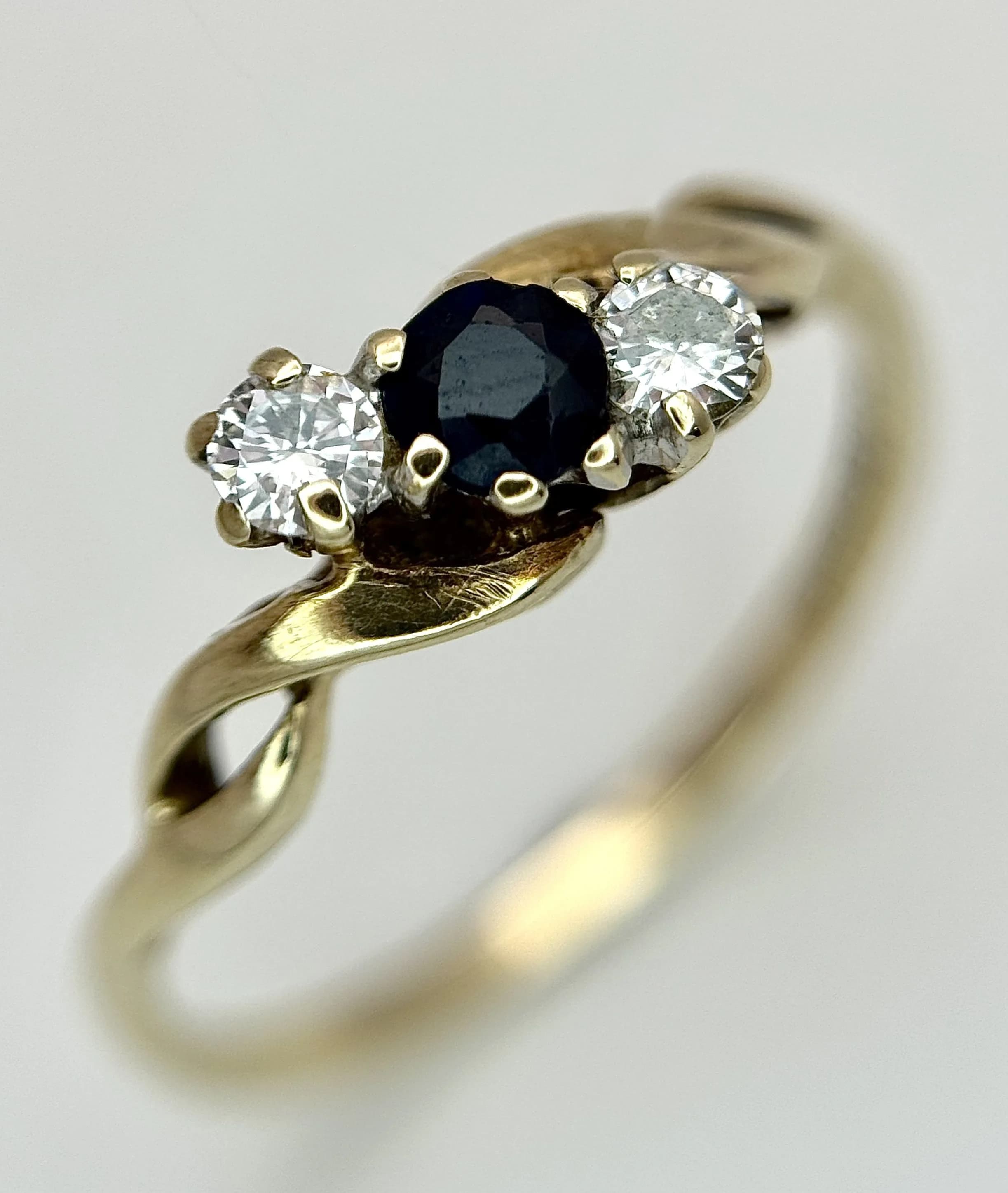 A 9K YELLOW GOLD, DIAMOND AND SAPPHIRE, 3 STONE, TWIST DESIGN RING. 0.10CTW. 1.1G, SIZE L. TAN 7005