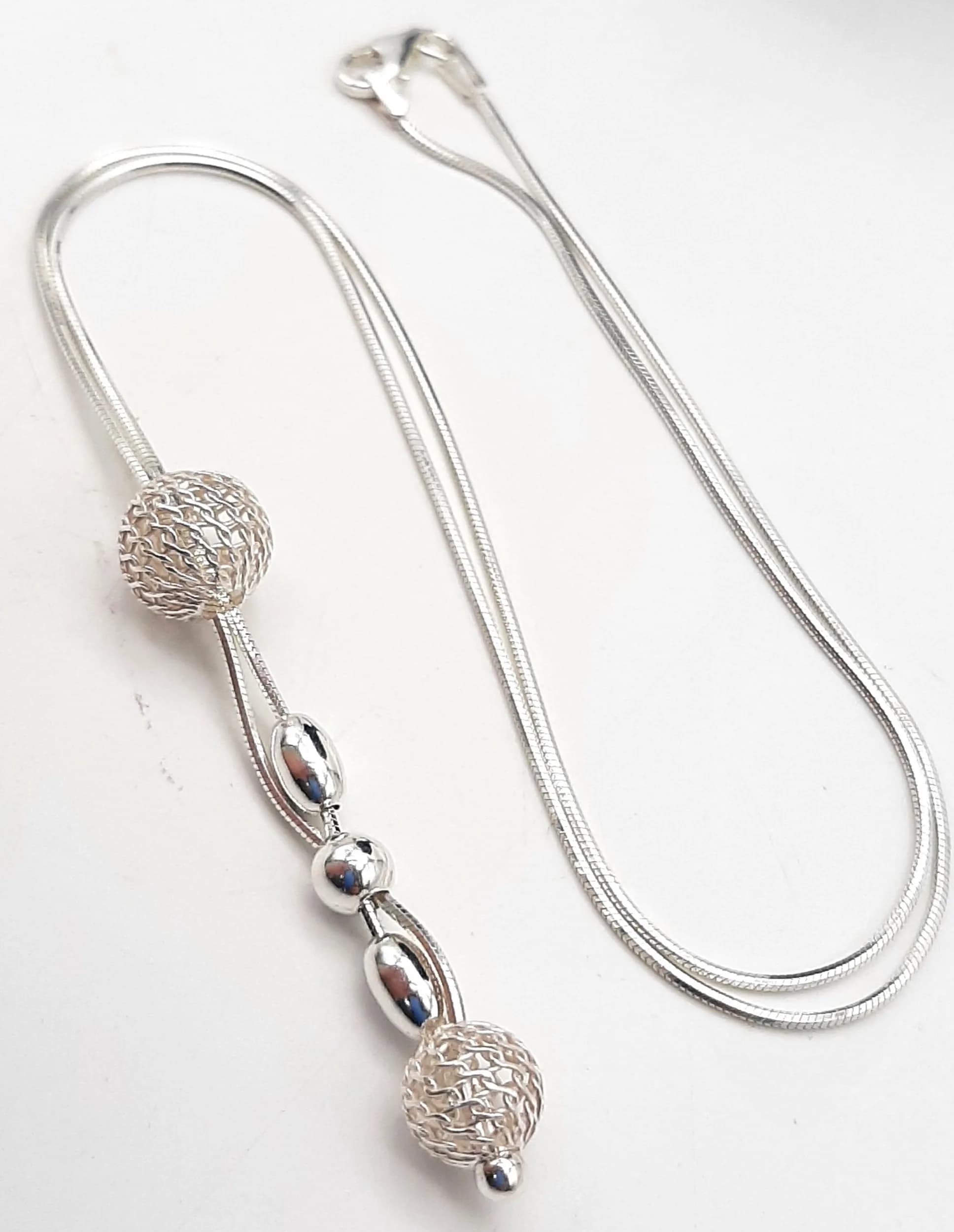 A 925 Silver Articulated Bead Pendant Necklace. Articulated pendant with removable pierced and polished silver beads on a fine snake chain. Hallmarked 925. Total weight 5.46 grams.