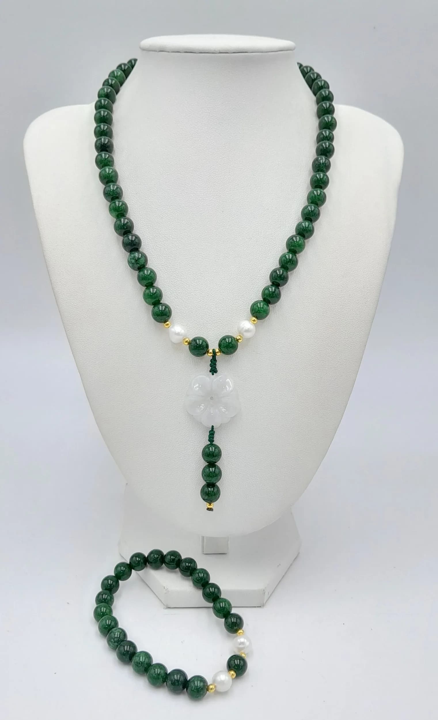 An elegant Green jade Necklace and Matching Bracelet Set. Comprising a green Jade necklace with pearls accent and a carved white Jade floral pendant drop, together with a matching elasticated bracelet. Necklace measures approx. 43cm in length. Please see photos or request a condition report.
