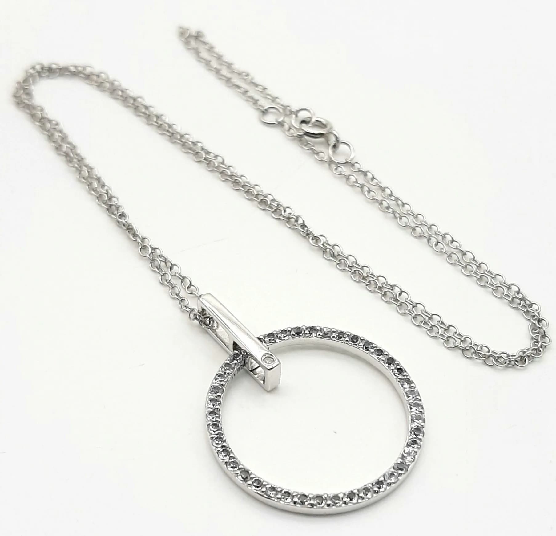 A 925 Silver White Stone Circle Pendant Necklace. Fine silver chain with a circular white stone set pendant and bar detail. Chain hallmarked 925, pendant unhallmarked. Approx 45cm chain length, pendant 3cm drop. Total weight 3.95 grams.