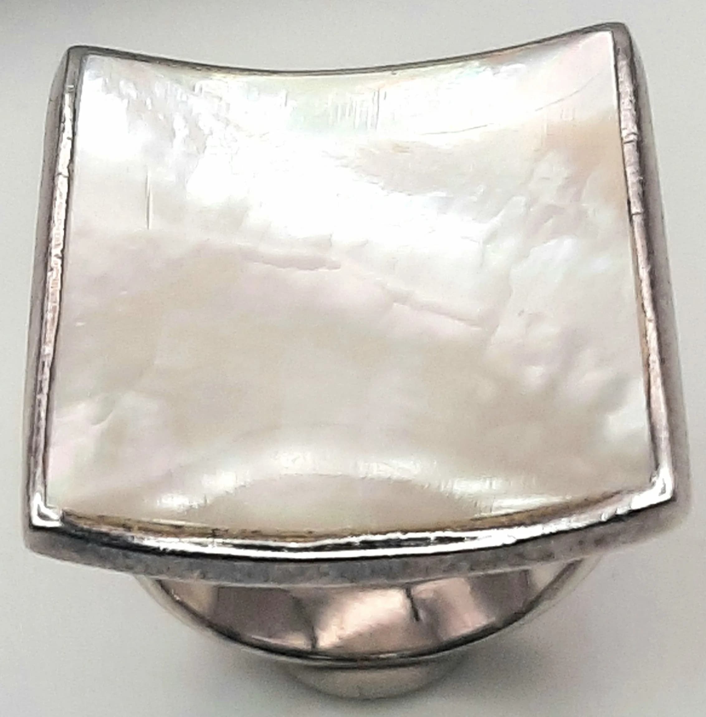 A 925 Silver Mother of Pearl Ring. Square curved mother of pearl panel in a polished silver setting. Hallmarked 925. Ring size N. Total weight 10.62 grams.
