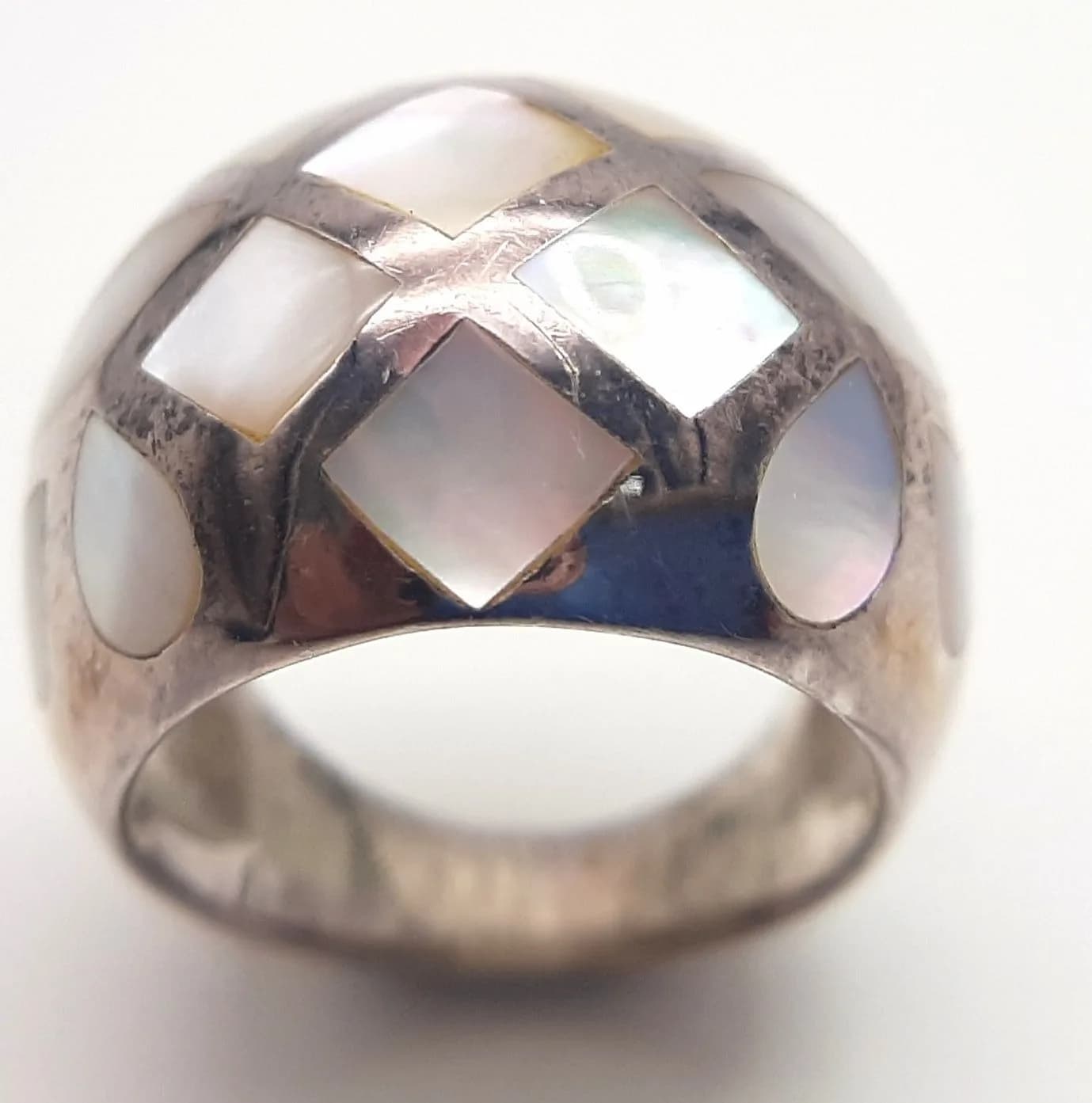 A 925 Silver Mother of Pearl Dome Ring. Wide polished band with mother of pearl inlay in a geometric design. Hallmarked 925. Ring size L. Total weight 9.71 grams.