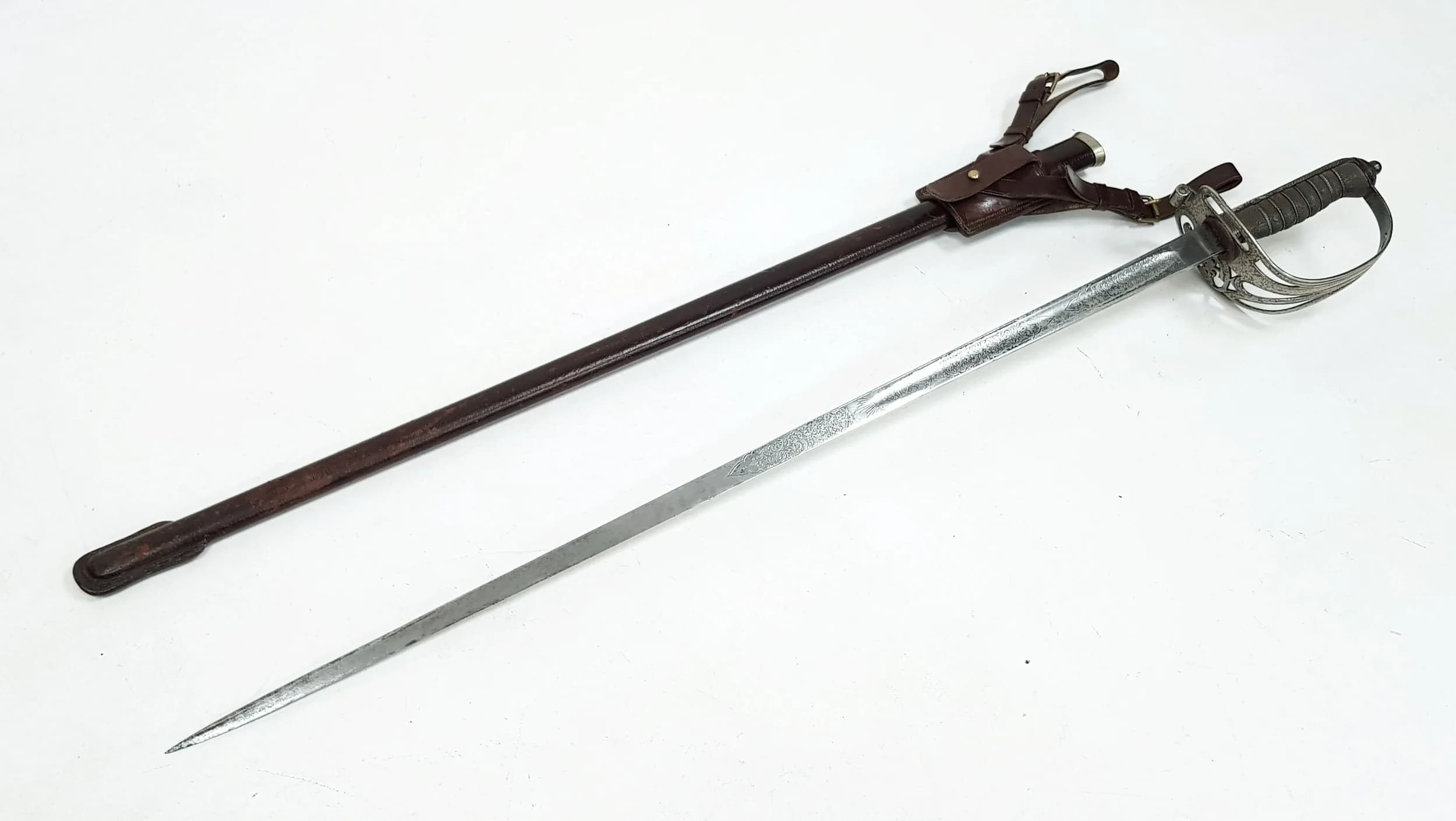 An 1827 Pattern Infantry Officers Sword. 1827 pattern hilt with Crowned strung bugle cartouche. Fish-skin grip with inlaid twisted wire. Engraved blade. Leather scabbard with leg straps. 105cm total length. UK Mainland Shipping Only or arrange a courier service.