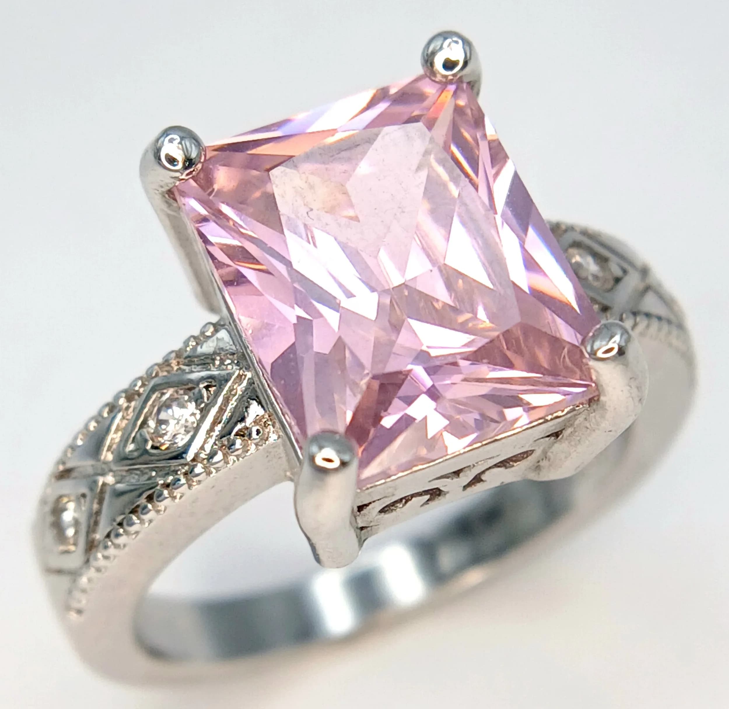 A Beautiful 925 Sterling Silver Pink Stone Ring. Size N. Set with a rectangular faceted pink stone measuring 1cm x 0.8cm, with white stone set shoulders. Gross weight 5.78 grams.
