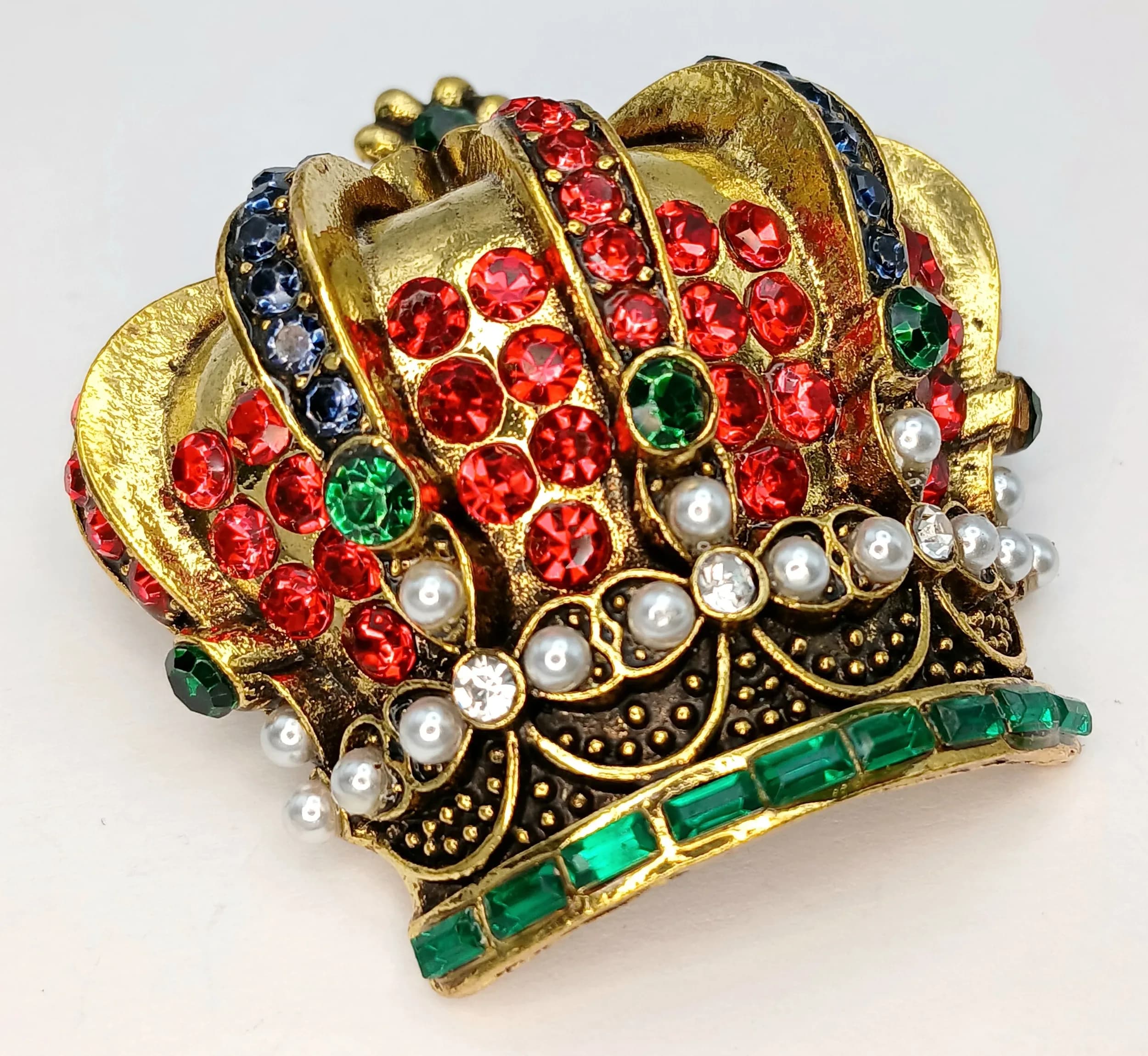A Decorative Gold-Tone Jewelled Crown Brooch. Set with red, green, blue and white stones in an ornate royal crown design. Approx. 5cm x 6cm.