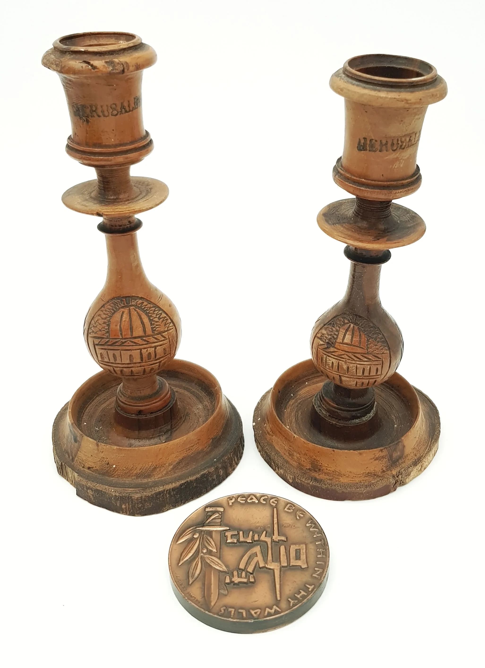 A Parcel of Vintage and Antique Jewish/Hebrew Items. Comprising: 1) A Vintage, Extremely Fine Condition, Hebrew-English Bronze Medal ‘Peace be within these walls’ 6cm Diameter. The medal also states ‘For the builders everyone had his sword by his side. 133 grams weight and 2) An Antique Pair of Hand-Crafted Wooden Candlesticks. 18cm Tall.