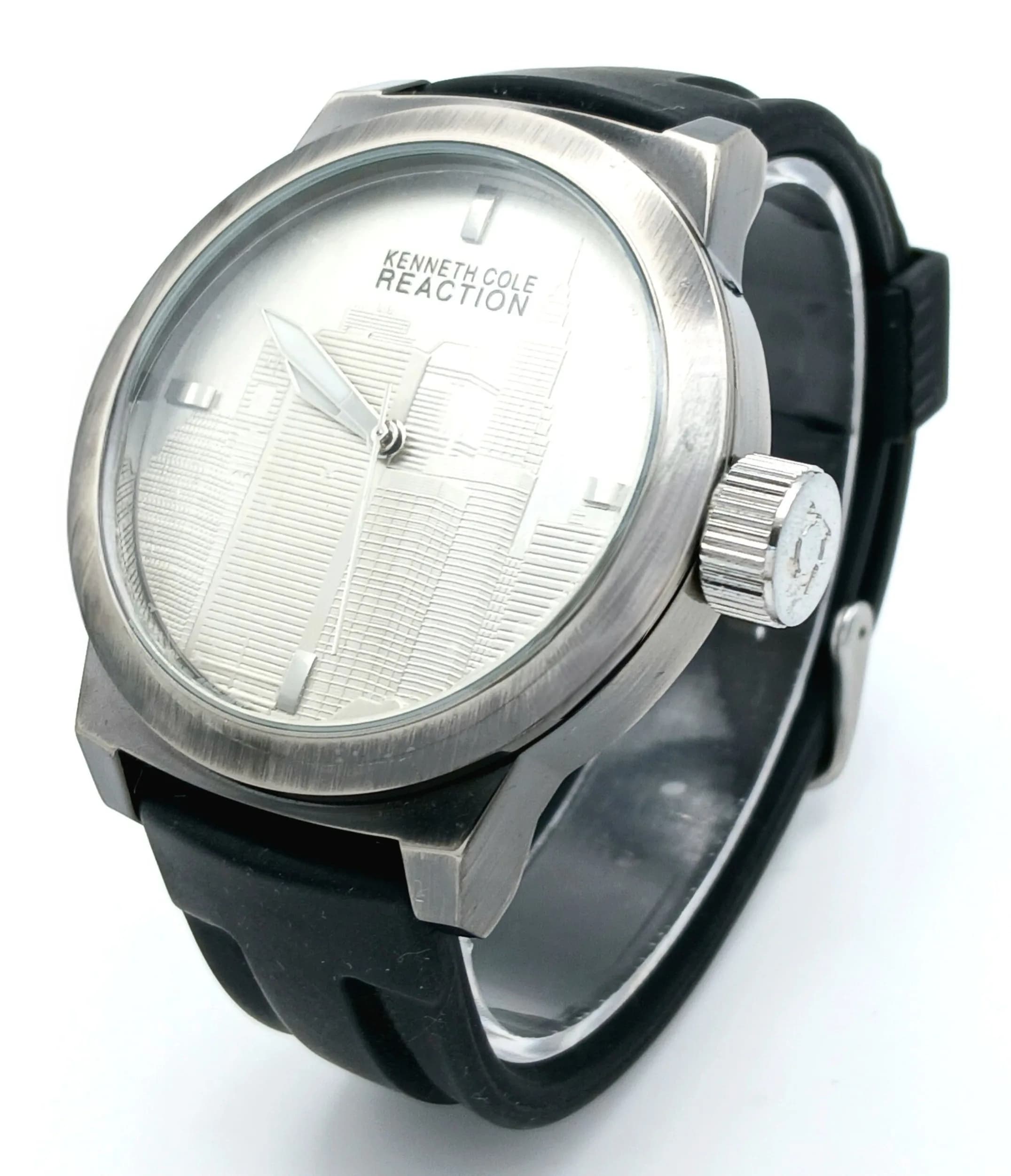 A KENNETH COLE REACTION WATCH, WITH A DISTINCTIVE CITYSCAPE SILVER DIAL, ON A BLACK RUBBER STRAP. IN FULL WORKING ORDER. MODEL RK1379. S/A 1704