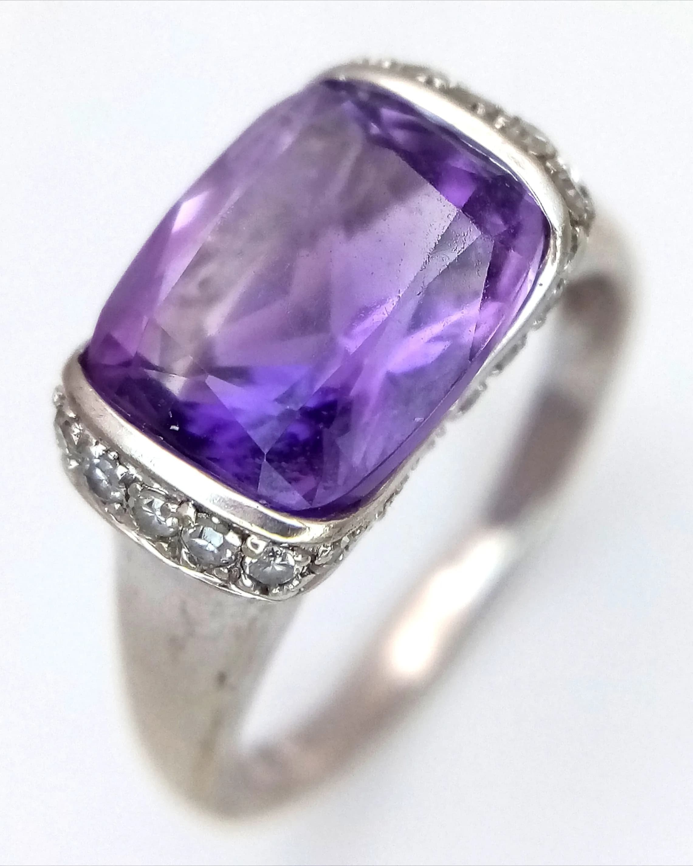 A 9K WHITE GOLD RING WITH CENTRAL AMETHYST SURROUNDED BY DIAMONDS . 3.4gms size N