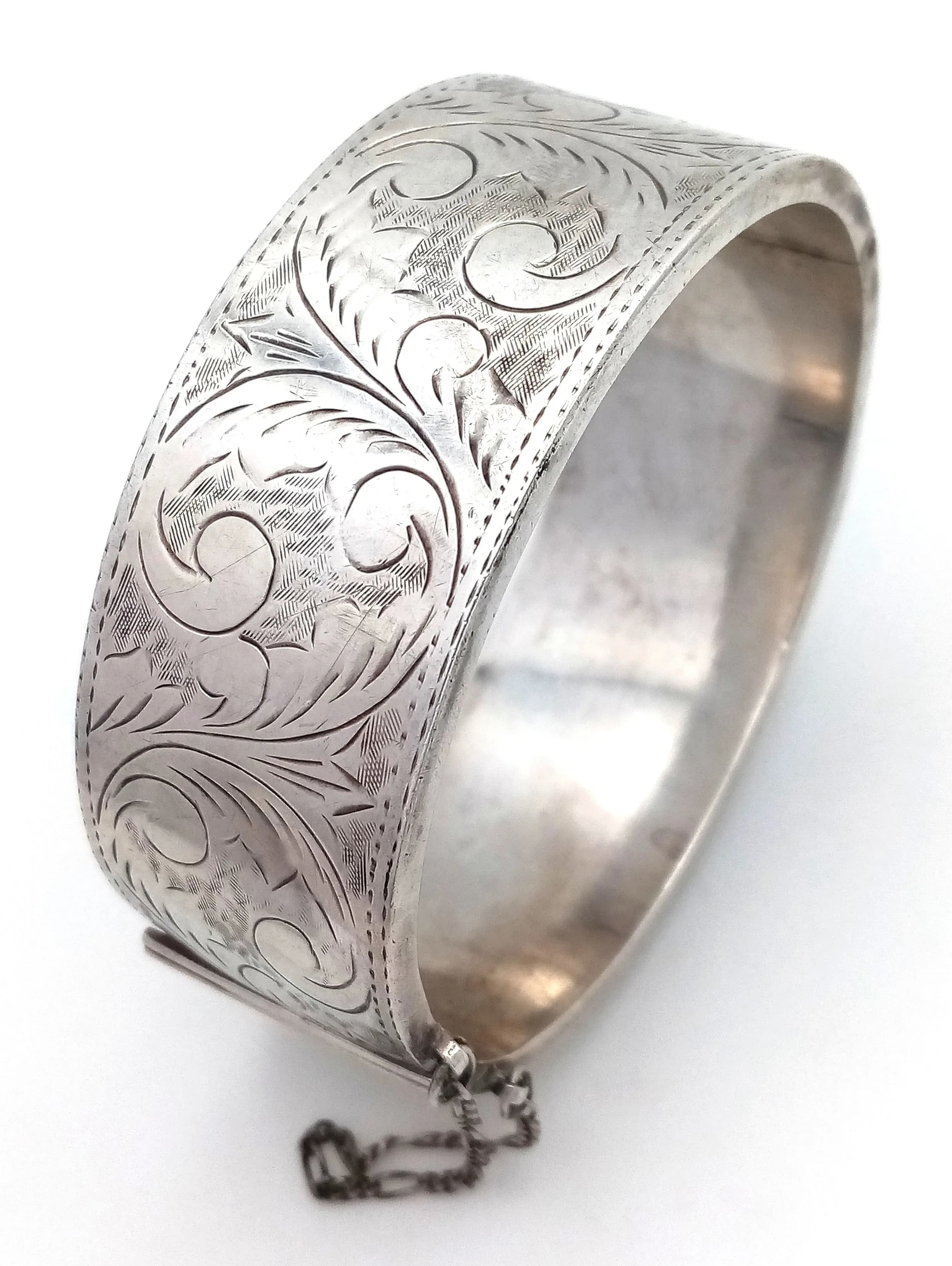 A Vintage Sterling Silver Bangle. 25mm width. Clip open design with safety chain. 40.8g.