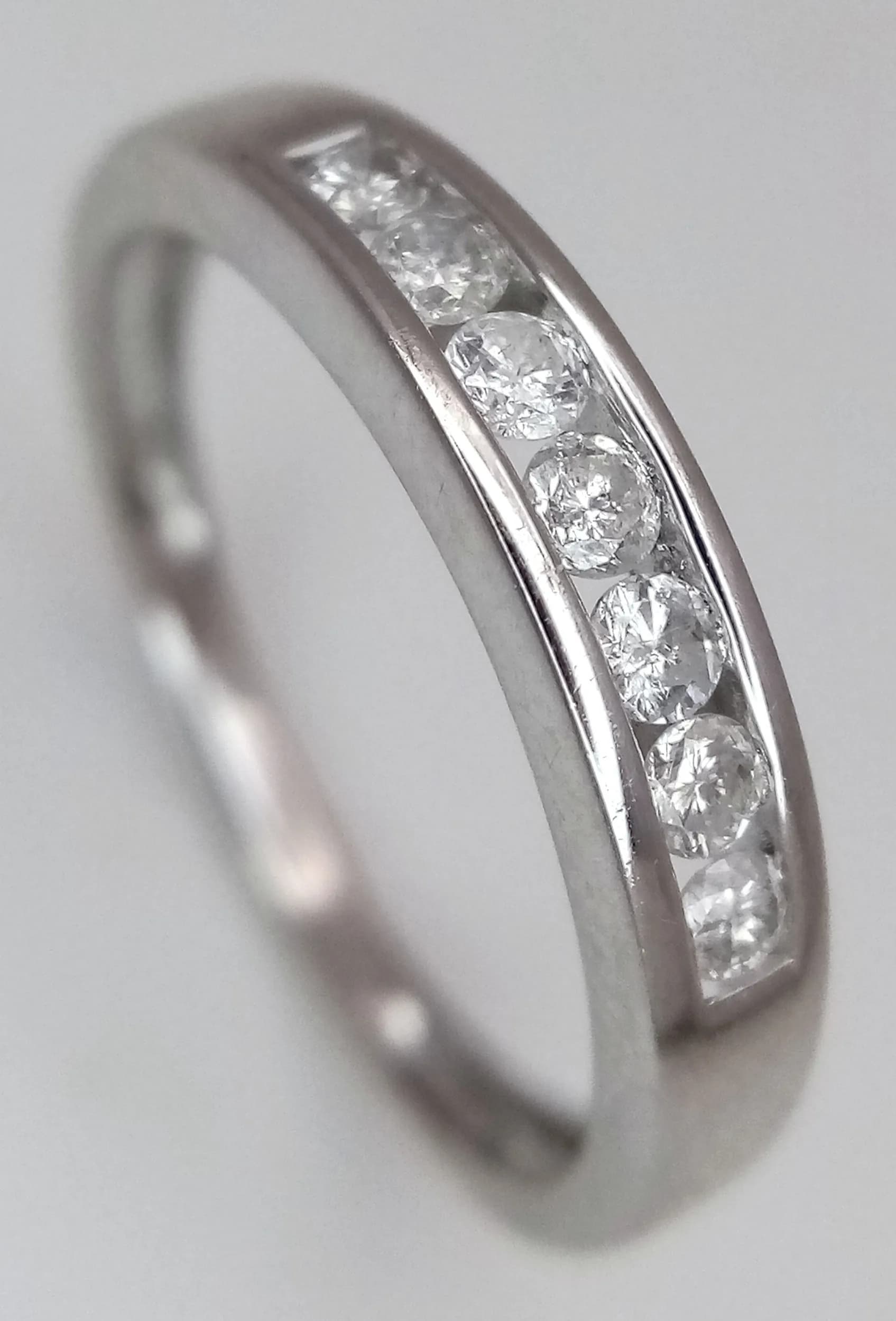 A 9K White Gold and Seven Stone Diamond Channel Set Ring.0.21ctw of round brilliant cut diamonds having H colour and SI1 clarity. Size M. 1.9g total weight. MT10.